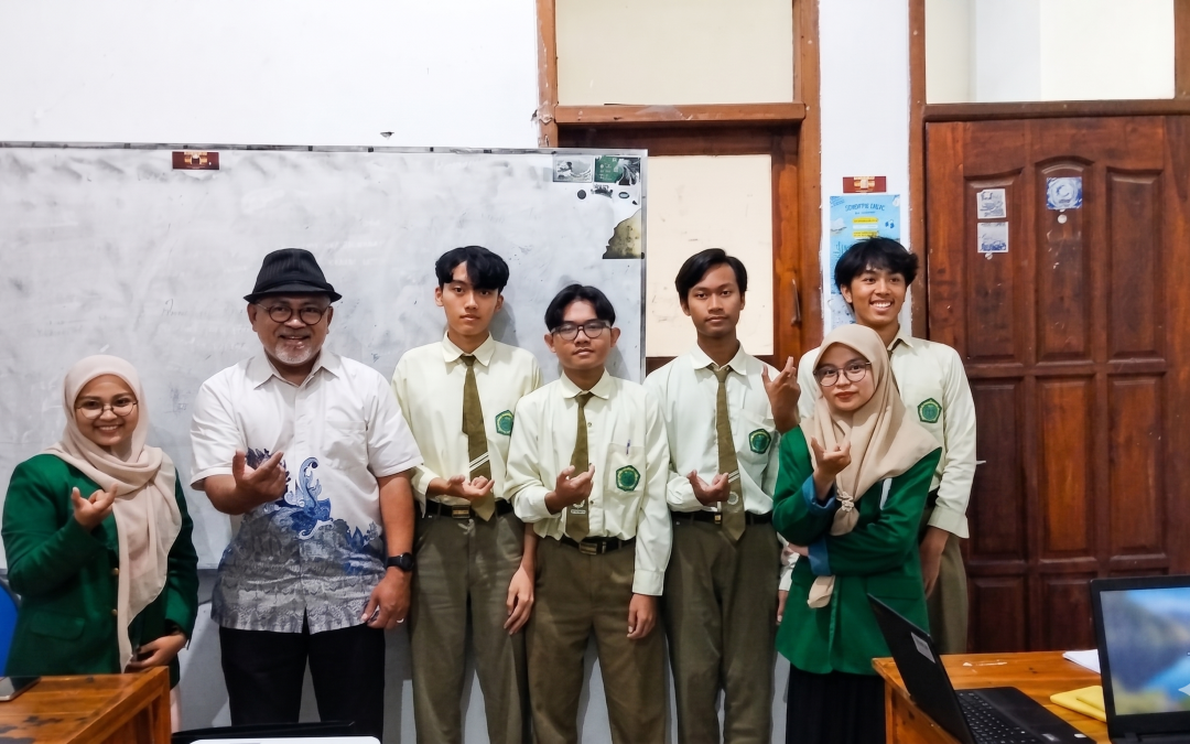 Foto bersama dosen, mahasiswa UNUSA berjas hijau, dan para siswa SMA Unggulan Amanatul Ummah di dalam kelas setelah kegiatan edukasi literasi keuangan.
